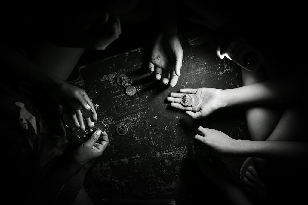 Monochrome image of hands exchanging coins on a table, creating a dramatic effect.